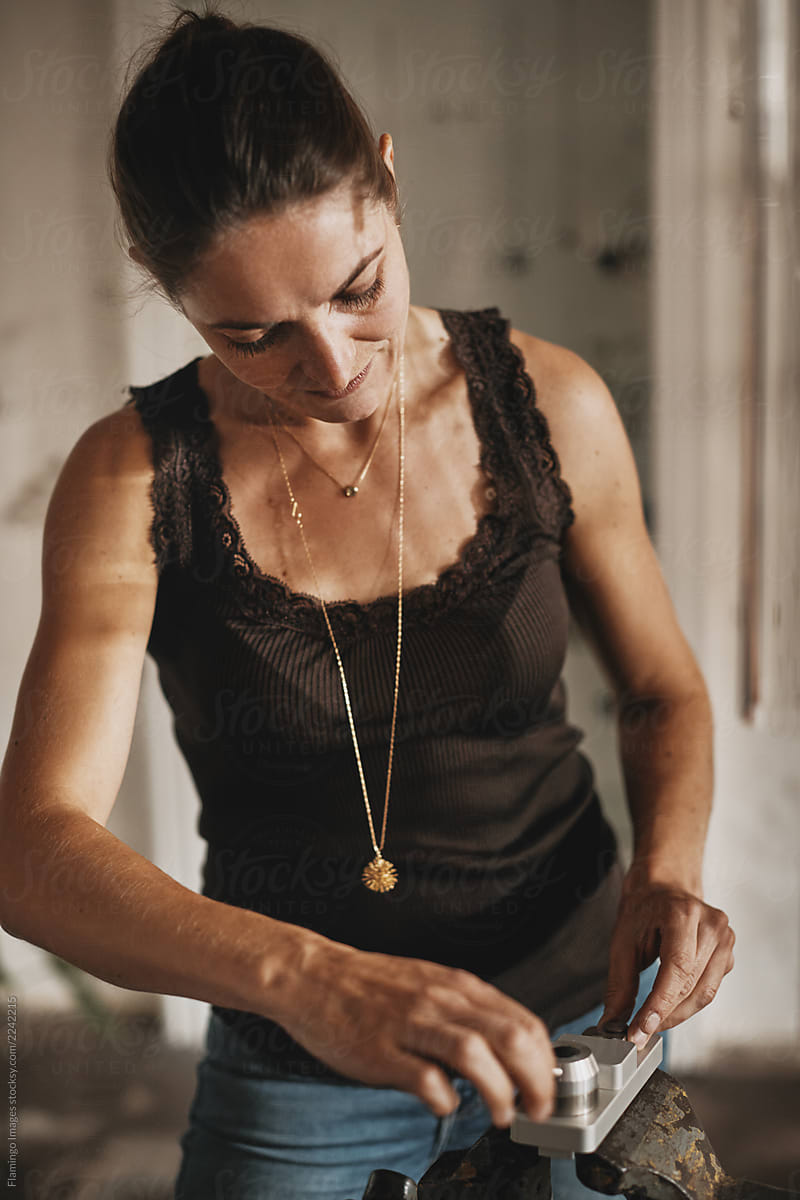 Female jeweler standing in her studio making jewelry