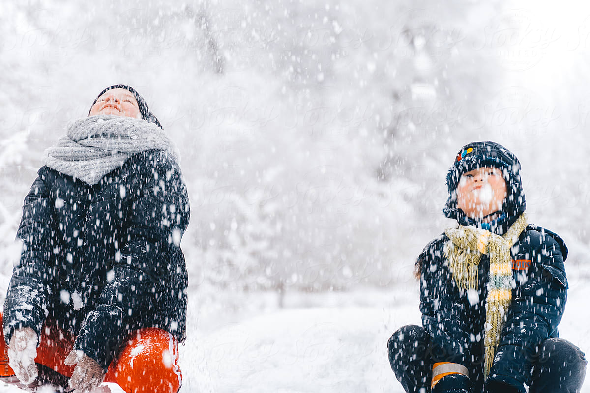 Children catching snowflakes enjoying wintertime in a snowy forest