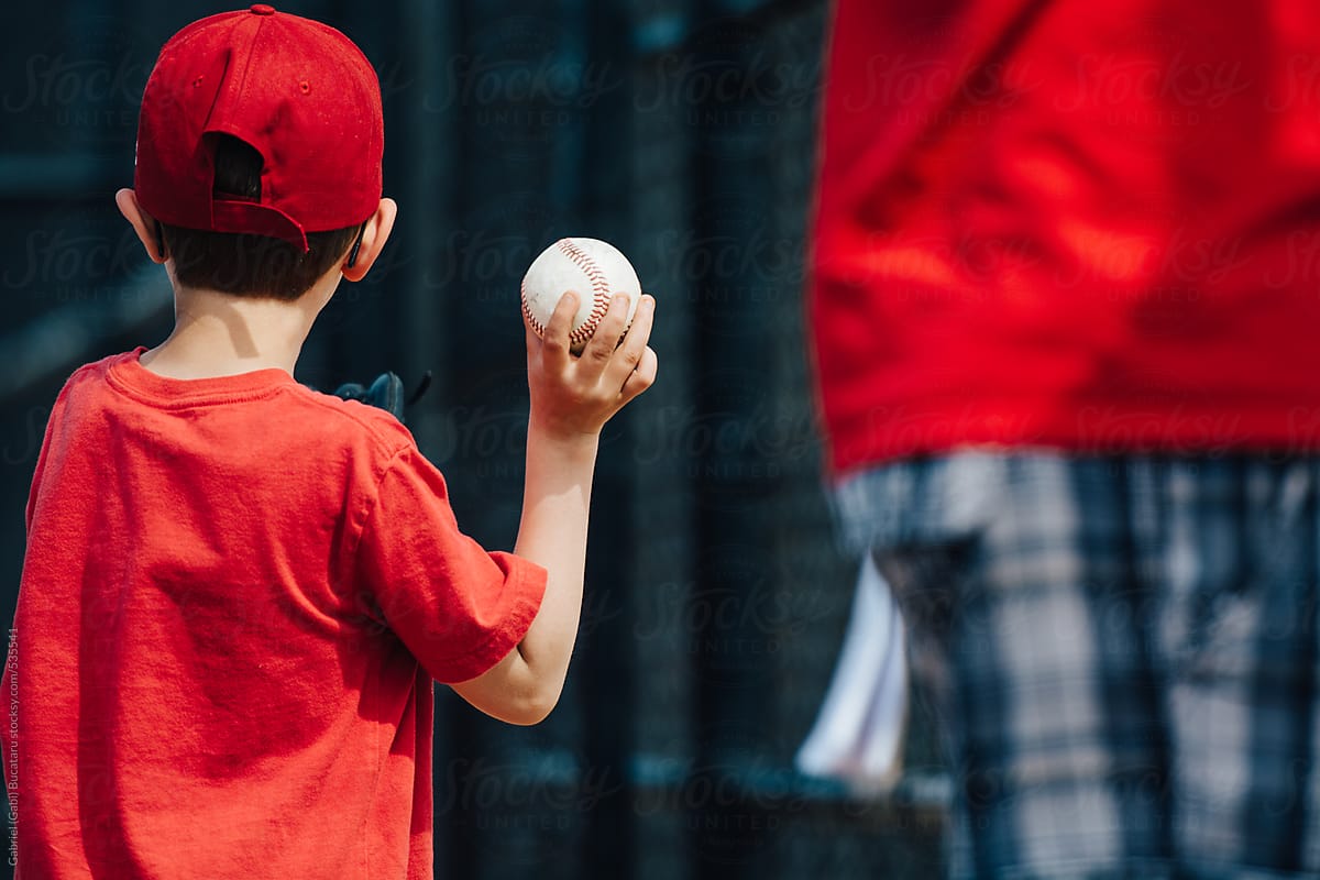 Young boy in red t shirt and cap, pitching a baseball