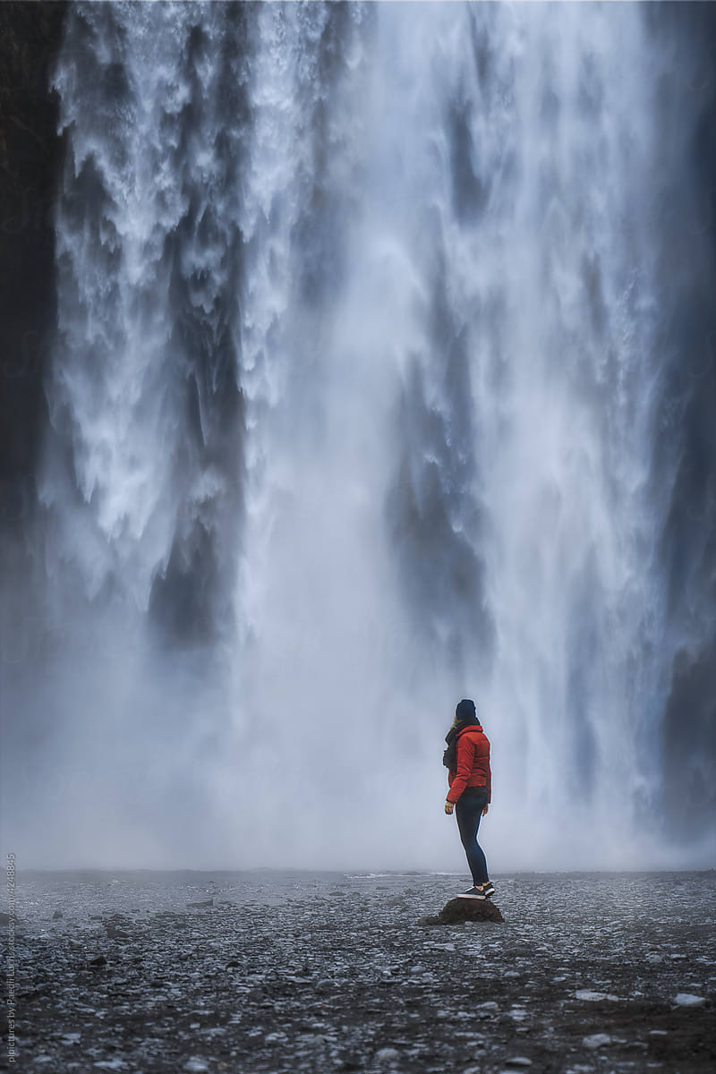 Woman standing in awe in front of an epic waterfall.