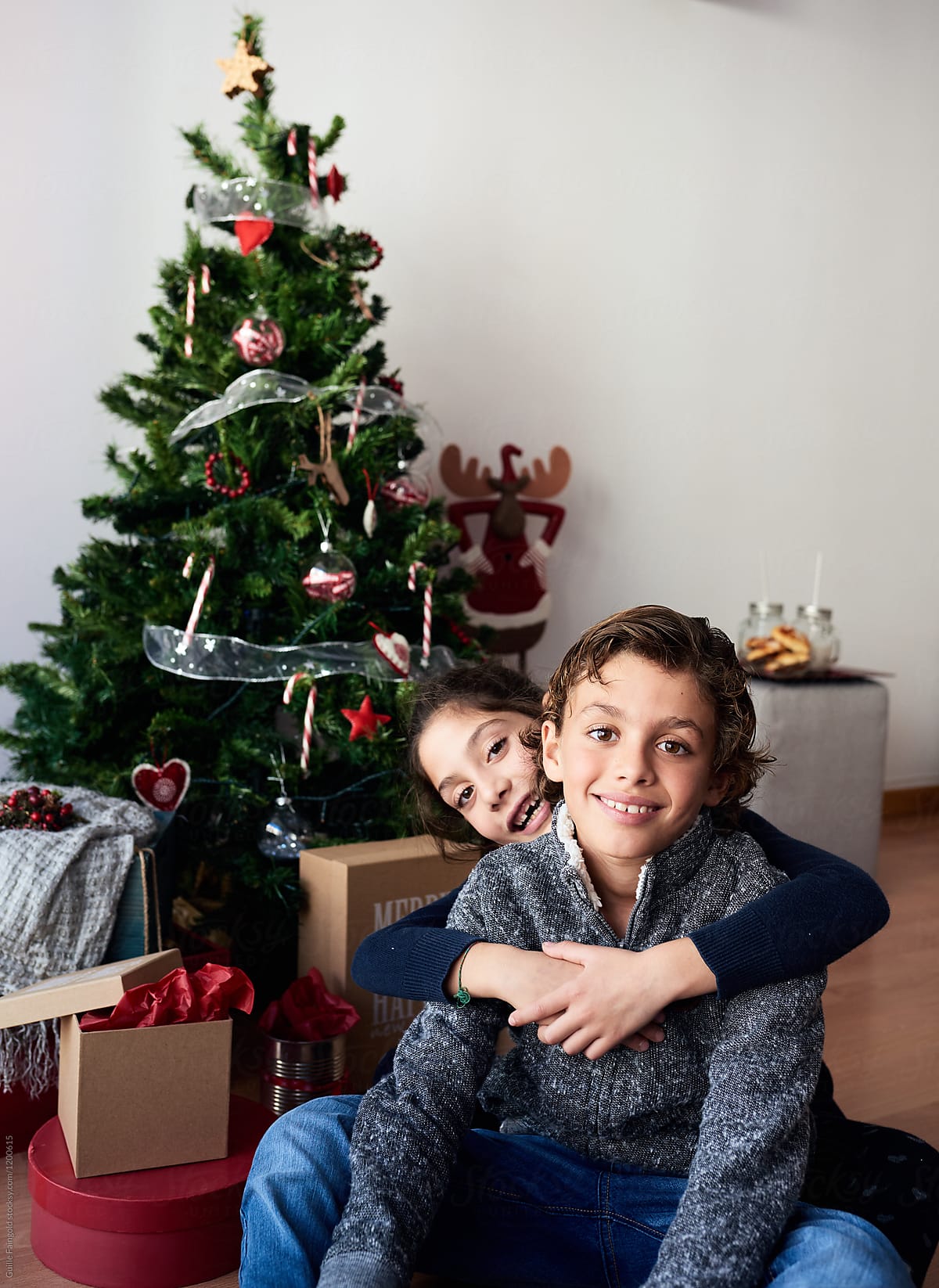 Brothers Sitting Against Christmas Tree By Guille Faingold
