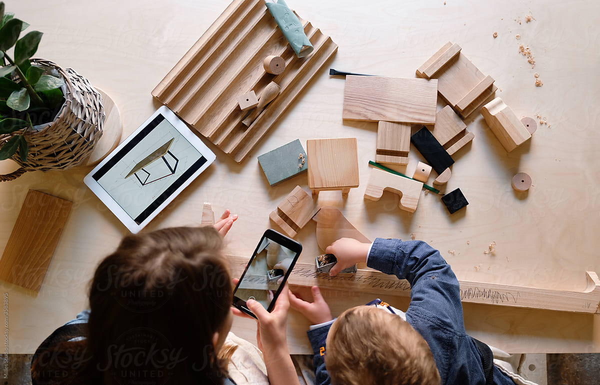 Woman taking photo of kid assembling wooden details