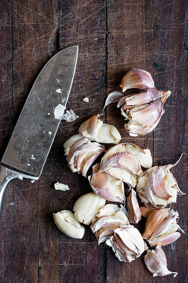 overhead view of smashed garlic cloves with a knife