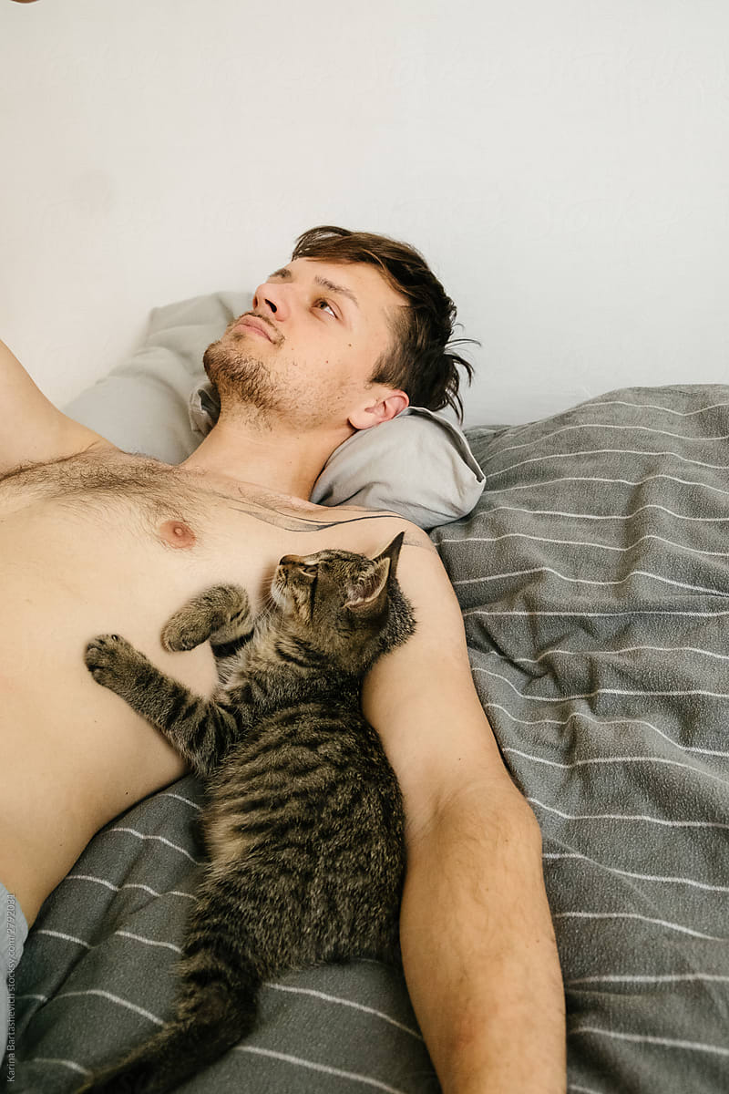 a kitten and a guy are lying nearby on a gray blanket in a friable apartment