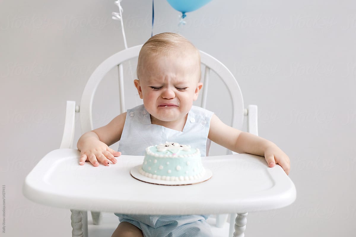 sad baby cries because he doesn\'t know how to eat his birthday cake