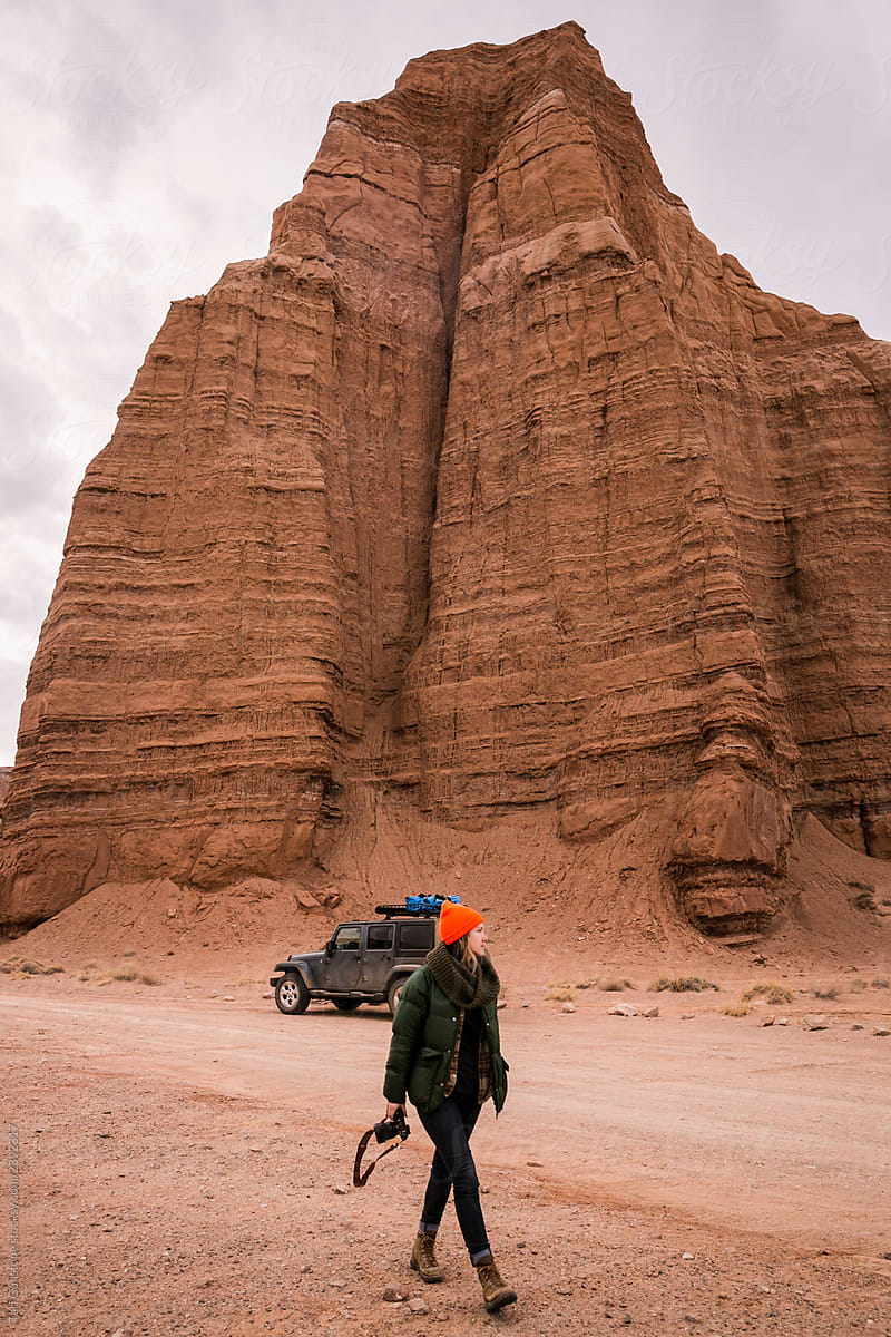 Woman, jeep, and the Temple of the Sun sandstone monolith in Utah desert