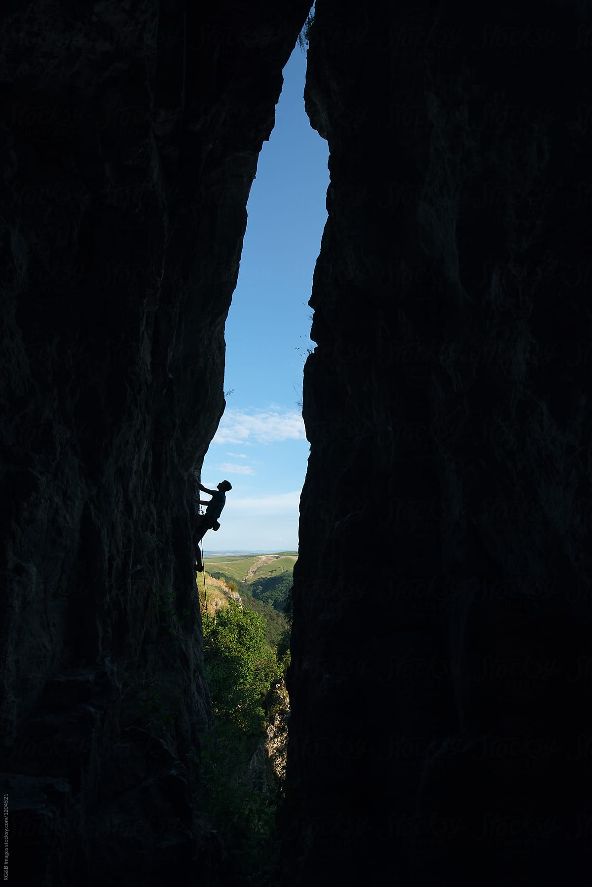 Male alpinist ascending on a vertical rock cave outdoor