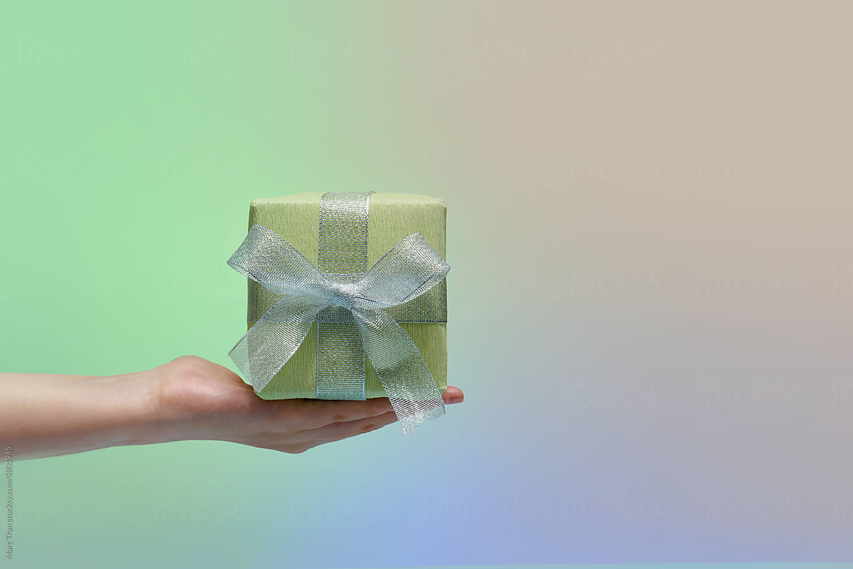 A woman's hand holding a green gift box