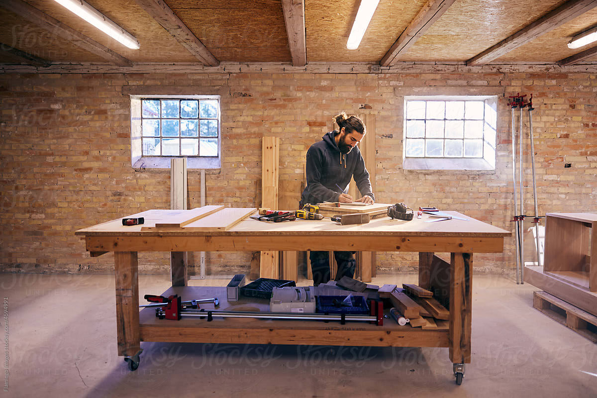 Woodworker writing notes at a bench in his studio