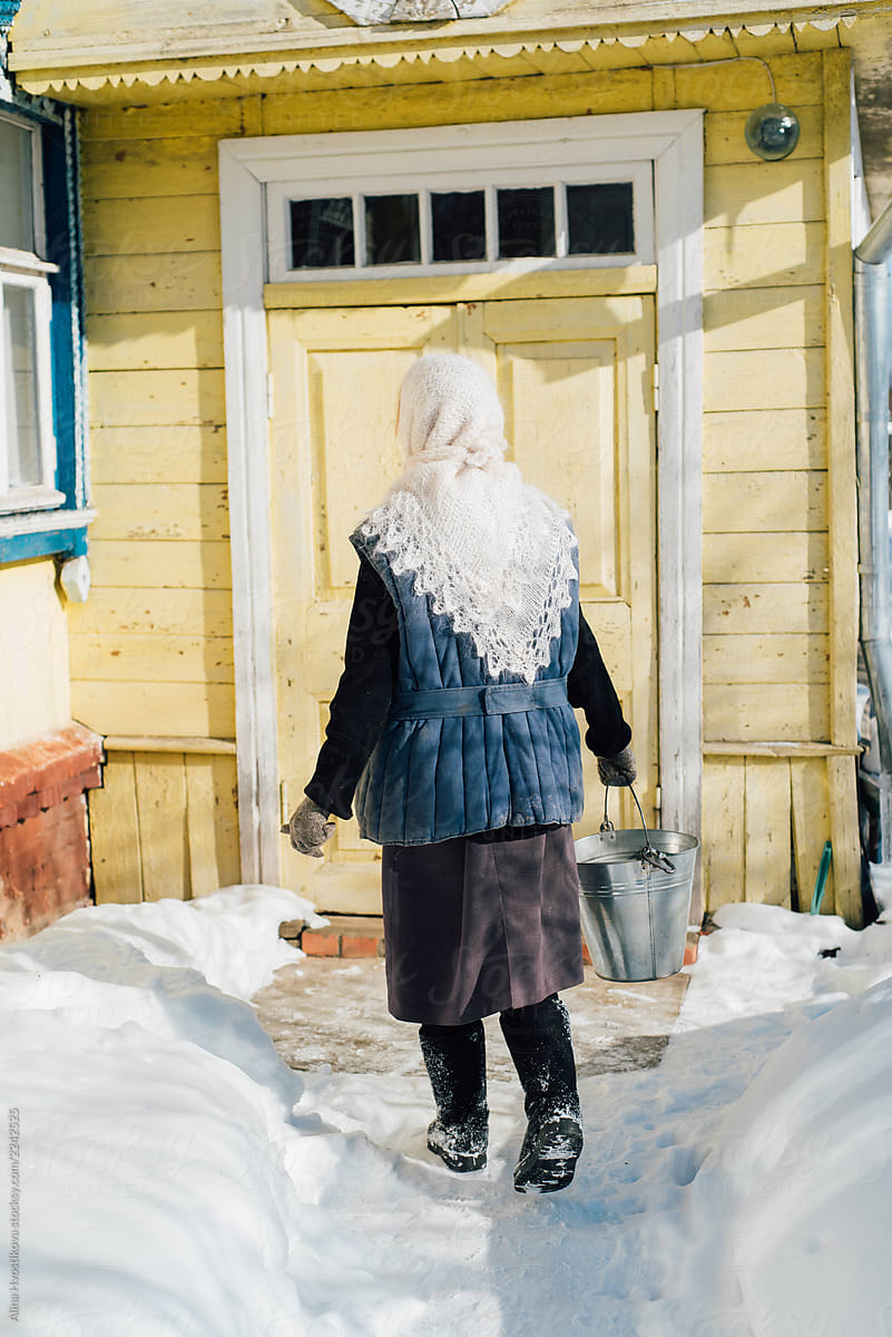 Anonymous woman carrying water in winter