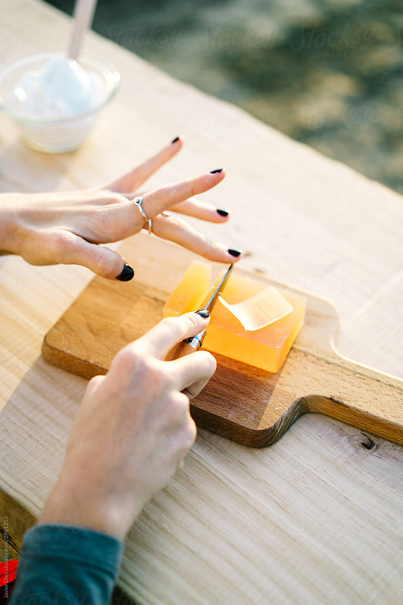 Hands of female model cutting soap  at wooden counter in street