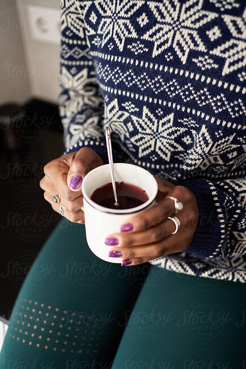 Unrecognizable woman having tea in kitchen in winter