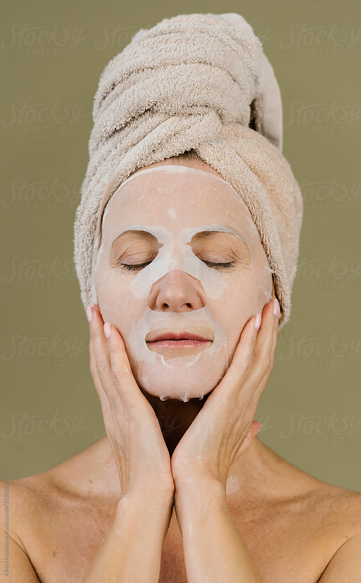 Peaceful woman with sheet facial mask in studio