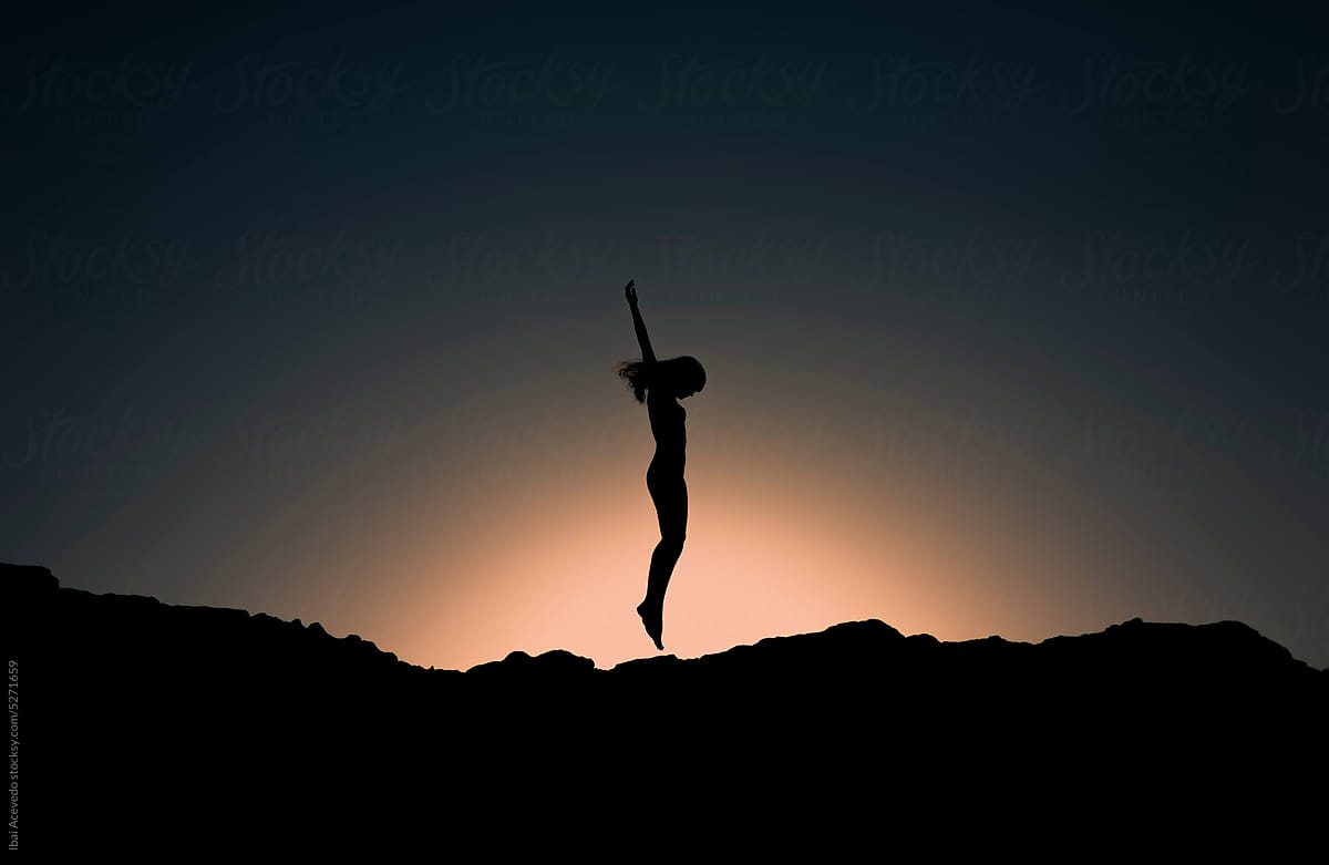 Woman silhouette jumping at surreal dark scenery