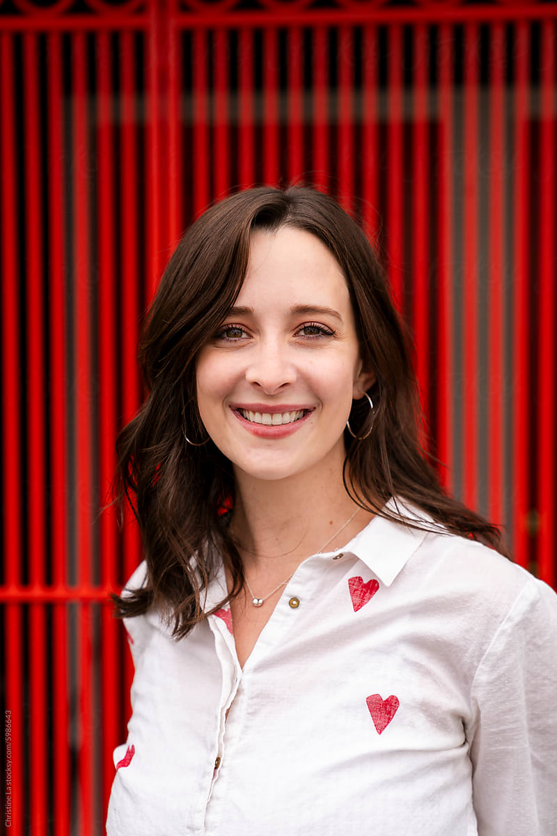 Portrait of smiling woman wearing hearts with red fence background