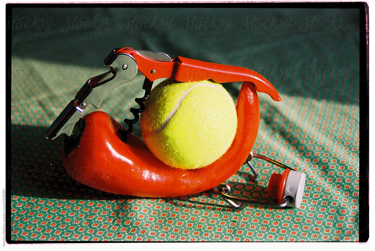 Conceptual still life with red pepper, an opener and a tennis ball.