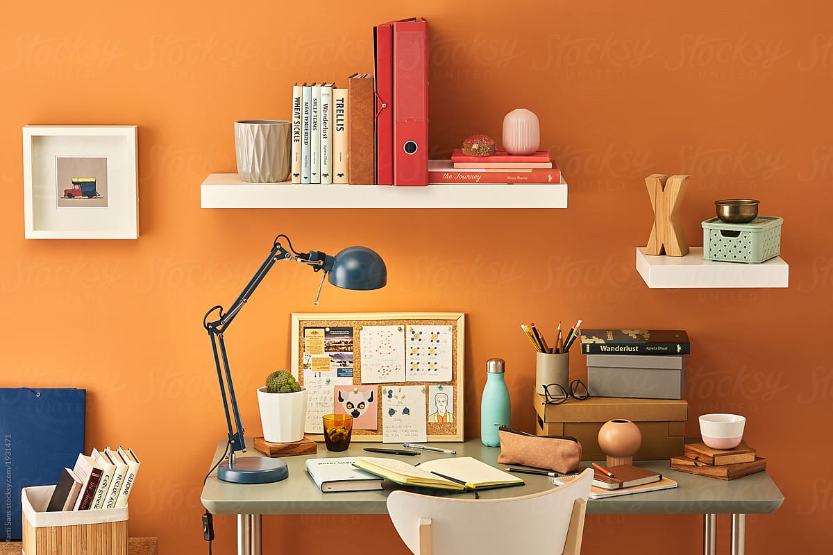 Messy student\'s workplace with orange wall.