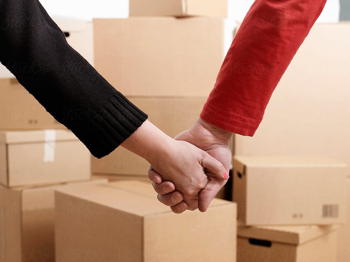 Couple holding hands surrounded by moving boxes