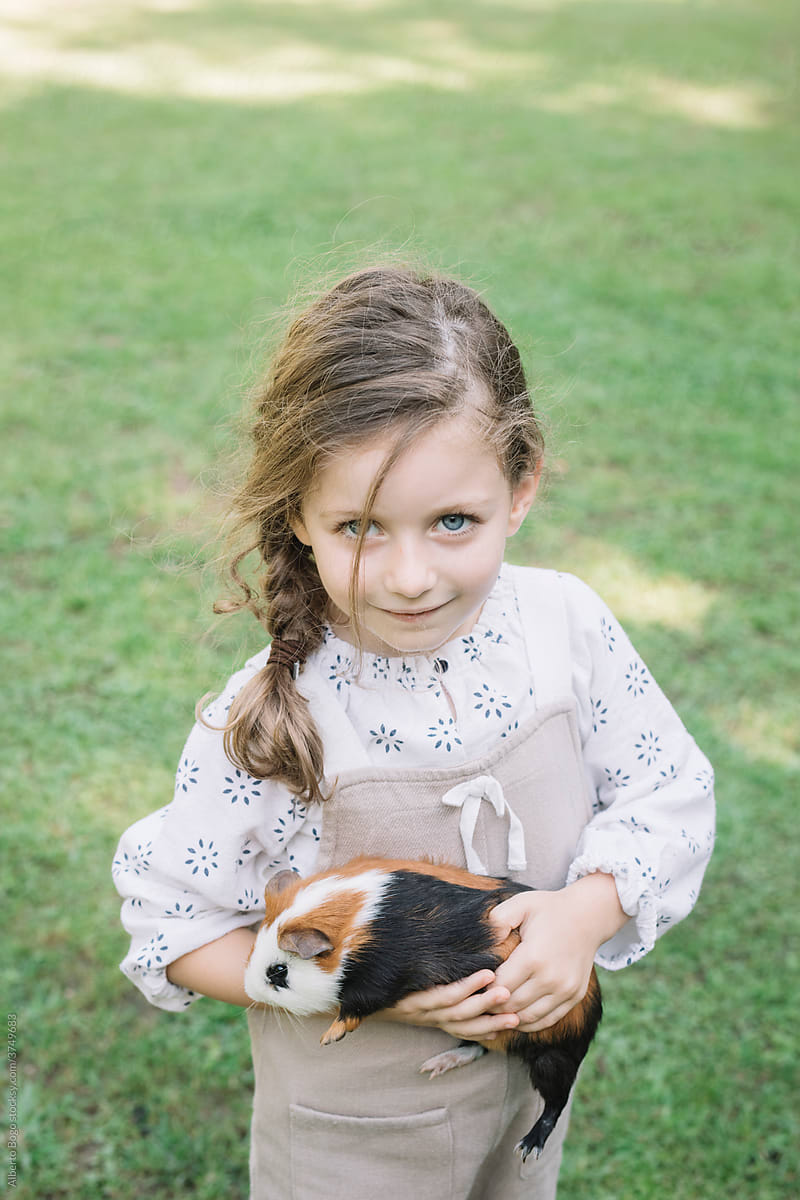 Smilling Little Girl Petting A Guinea Pig At Farm