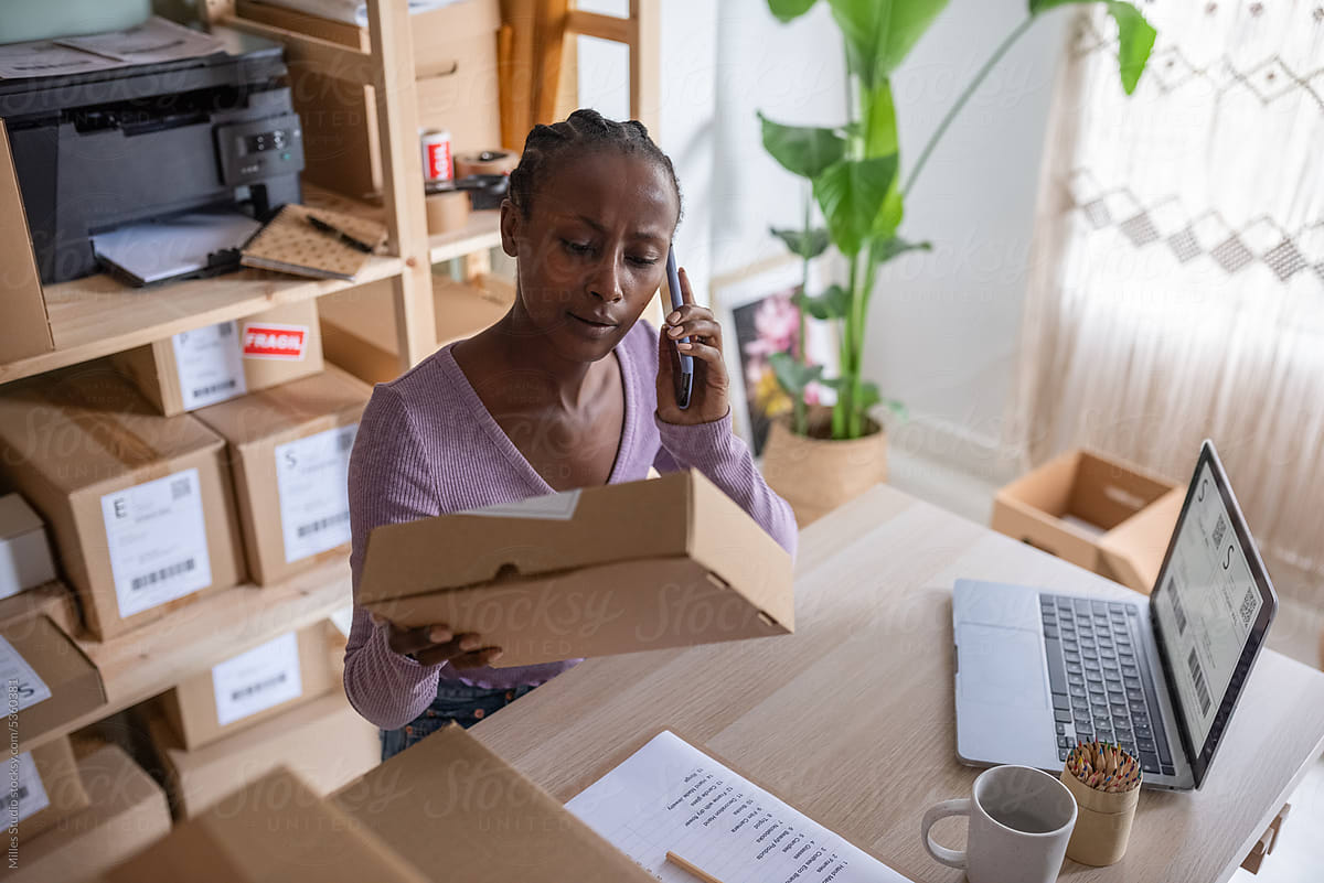 Black woman reading address label during phone call