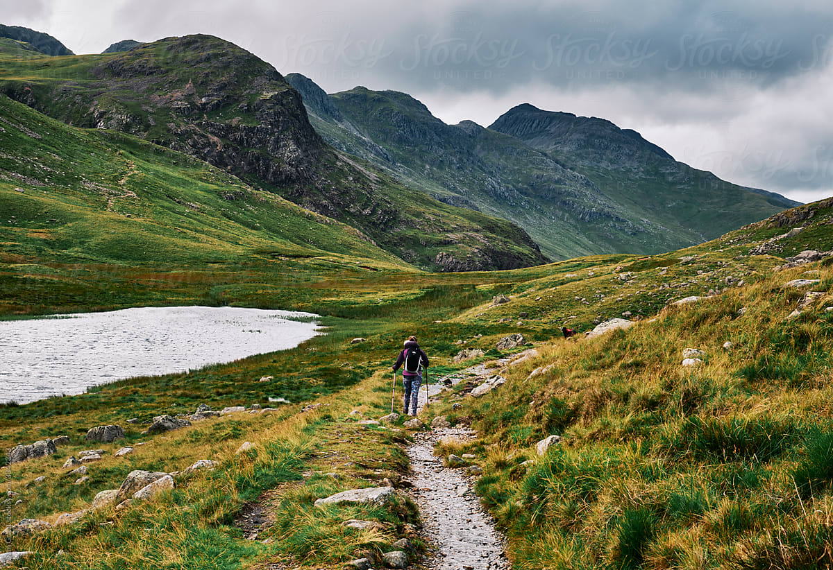 Female walking past Red Tarn on route to Pike of Blisco. Lake District, Cumbria, UK.