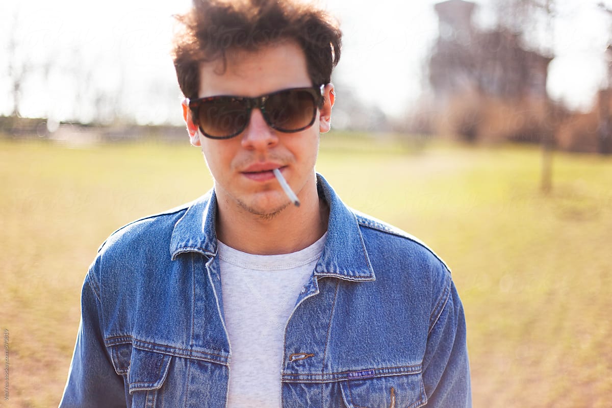 Young man with denim jacket and sunglasses in the park