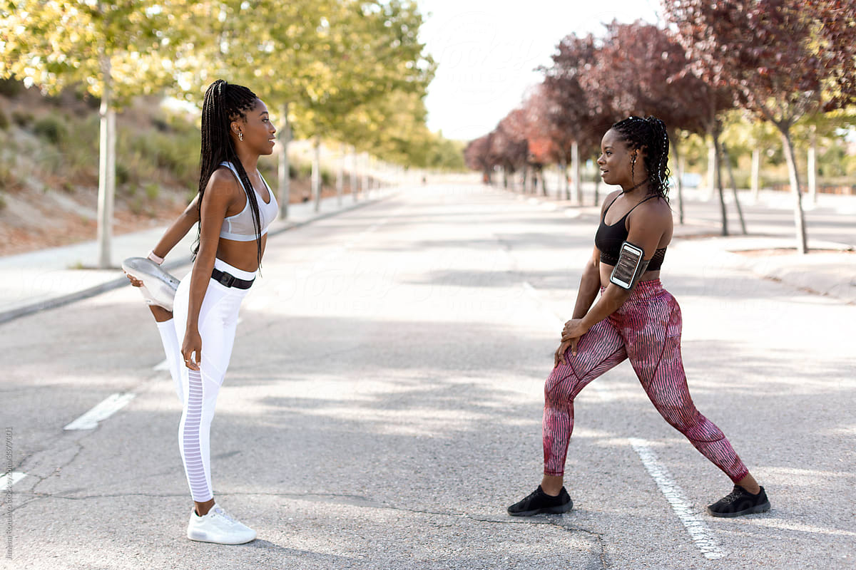 Two women friends stretching before start training