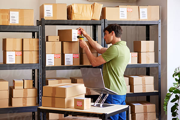 Young Logistic Manager Organizing Boxes In Storage by Stocksy