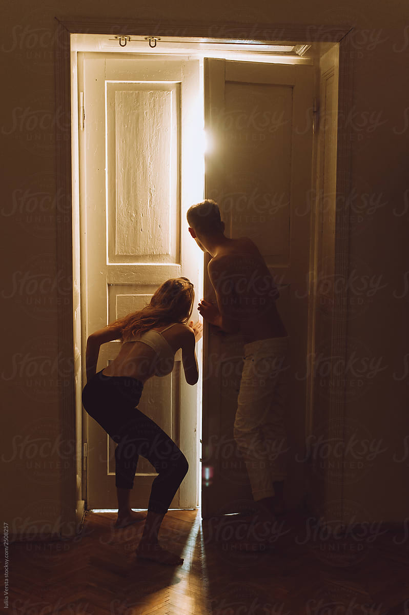 Silhouette of girl and boy standing near luminous door
