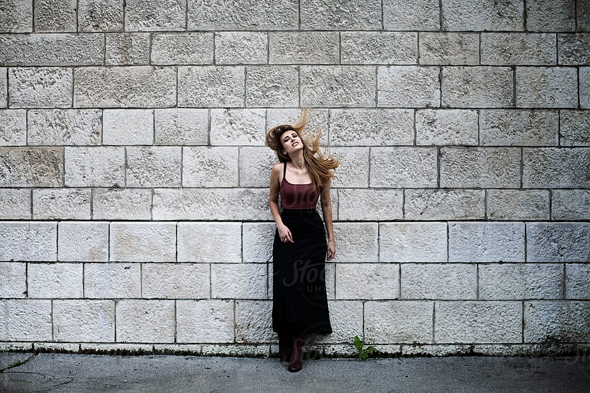 Young Woman With Long Hair In A Dress By The Wall By Stocksy