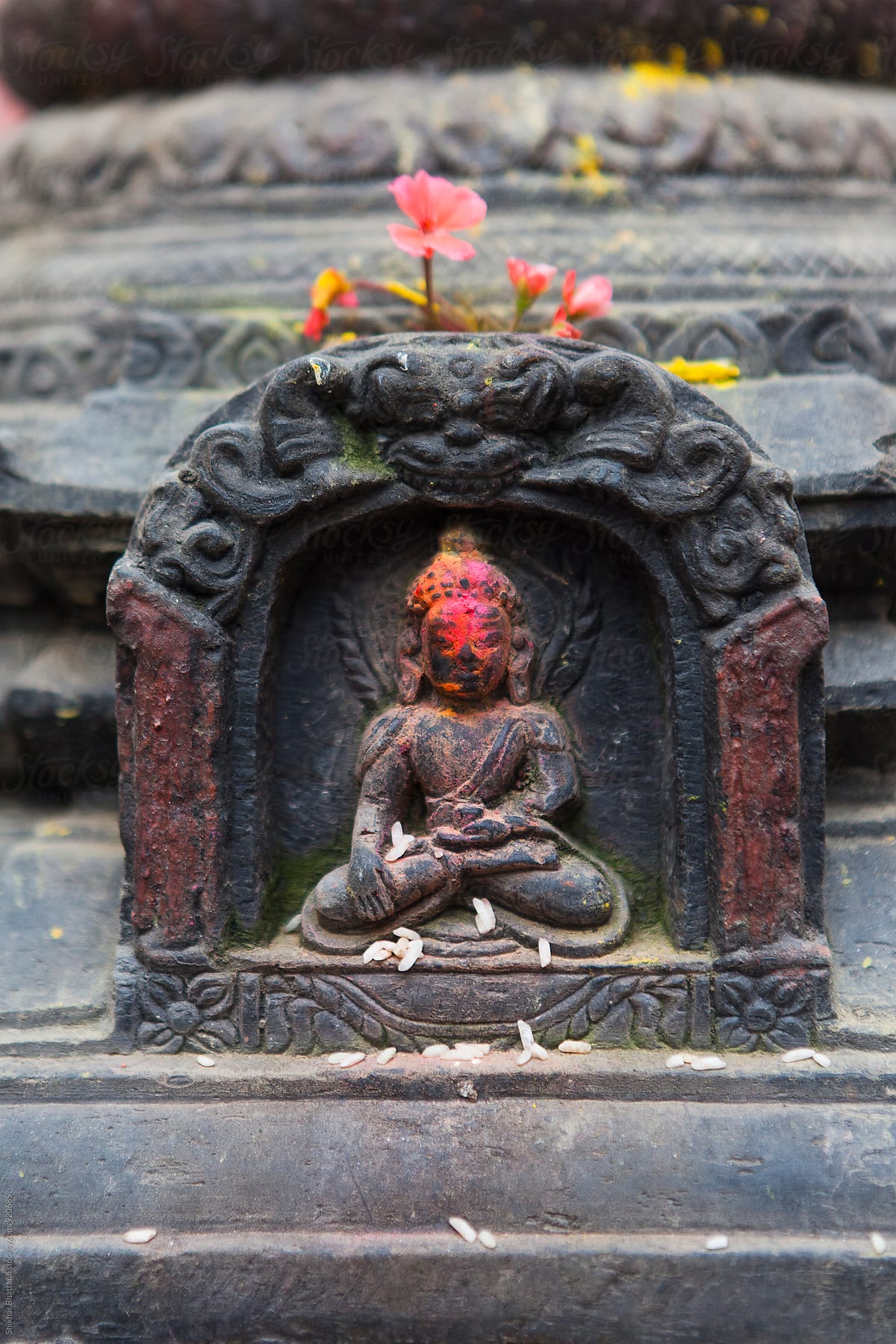 Small stone sculpture of Buddha covered in vermillion powder, Nepal.
