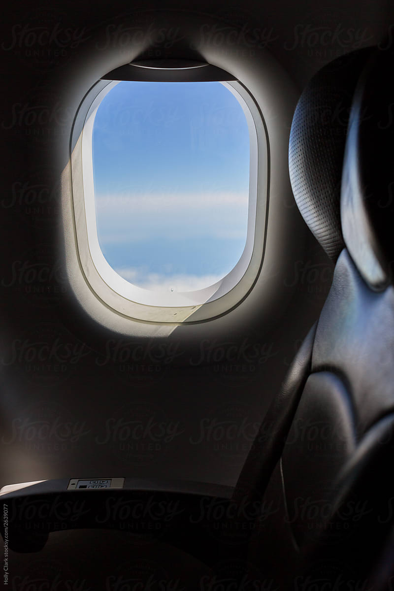 Airplane Window next to empty seats with blue sky
