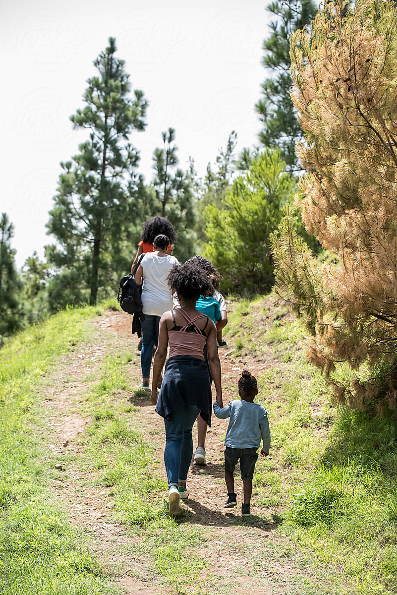 Black family walking on path in woods with children