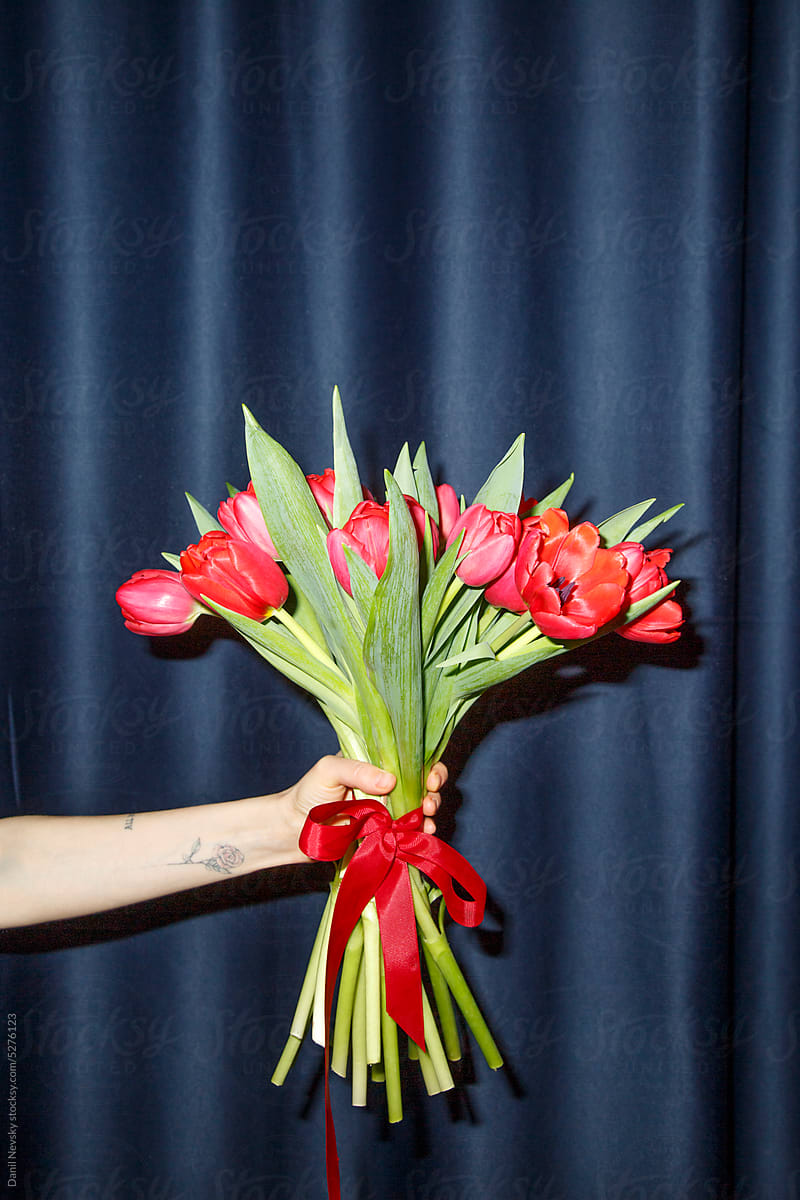 Crop hand with bouquet of tulips