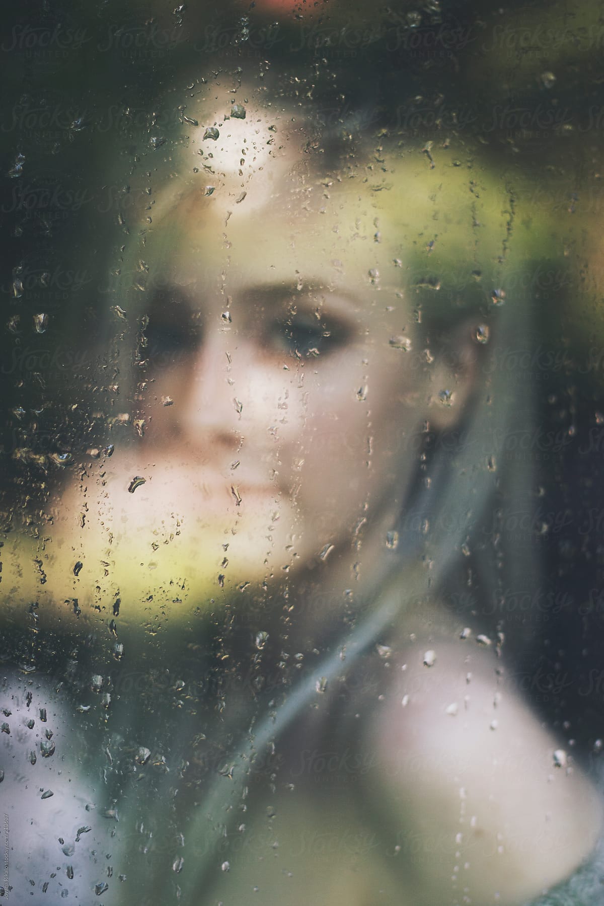 Beautiful young woman  woman standing at the window watching the rain