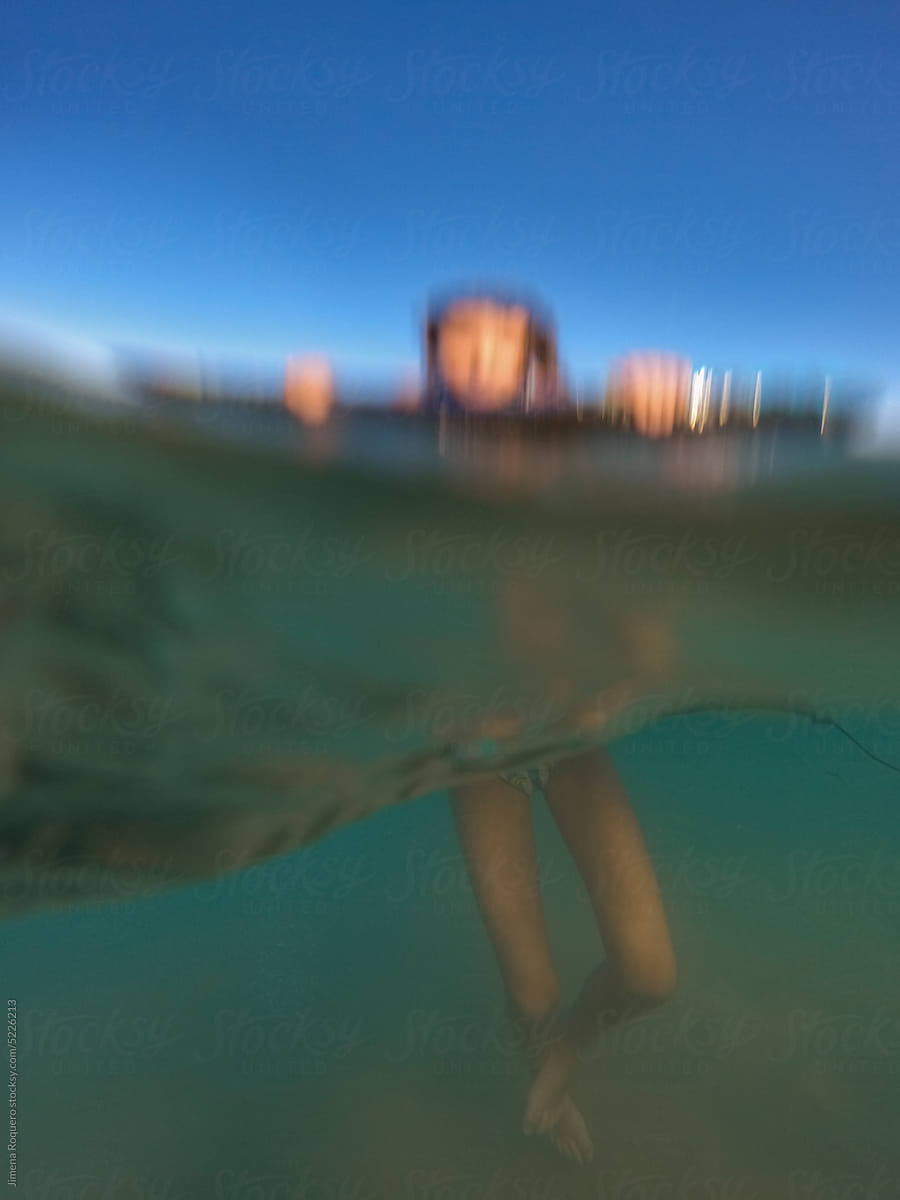 UGC underwater blurry shot. Kid in the sea on bodyboard over blue sky