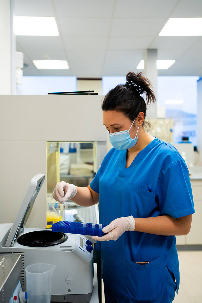Woman With Mask And Blue Uniform Working In The Lab.