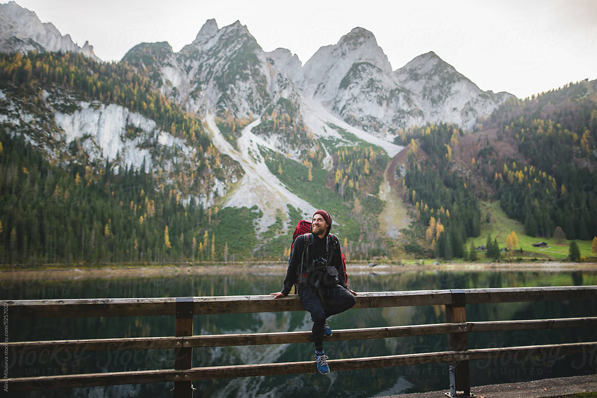 Backpacker Sitting Near Lake And Mountain Range