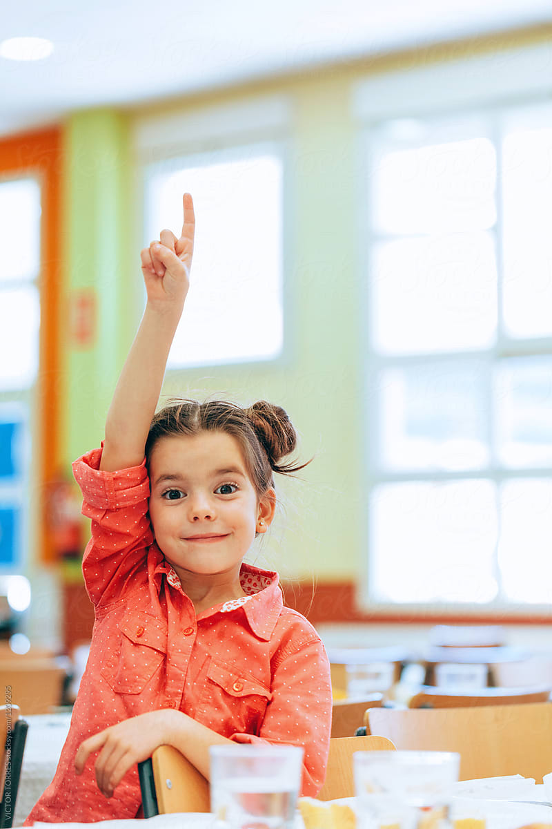 Adorable girl raising hand at school canteen