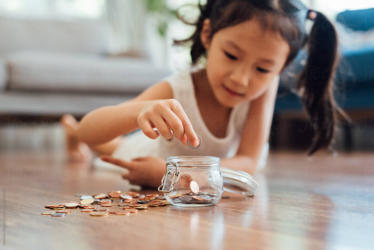 Adorable girl putting coins in jar