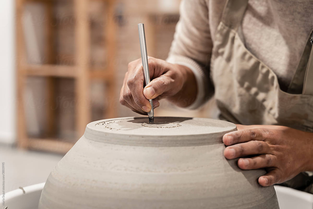 Ceramist grinds a future bowl on a potter\'s wheel