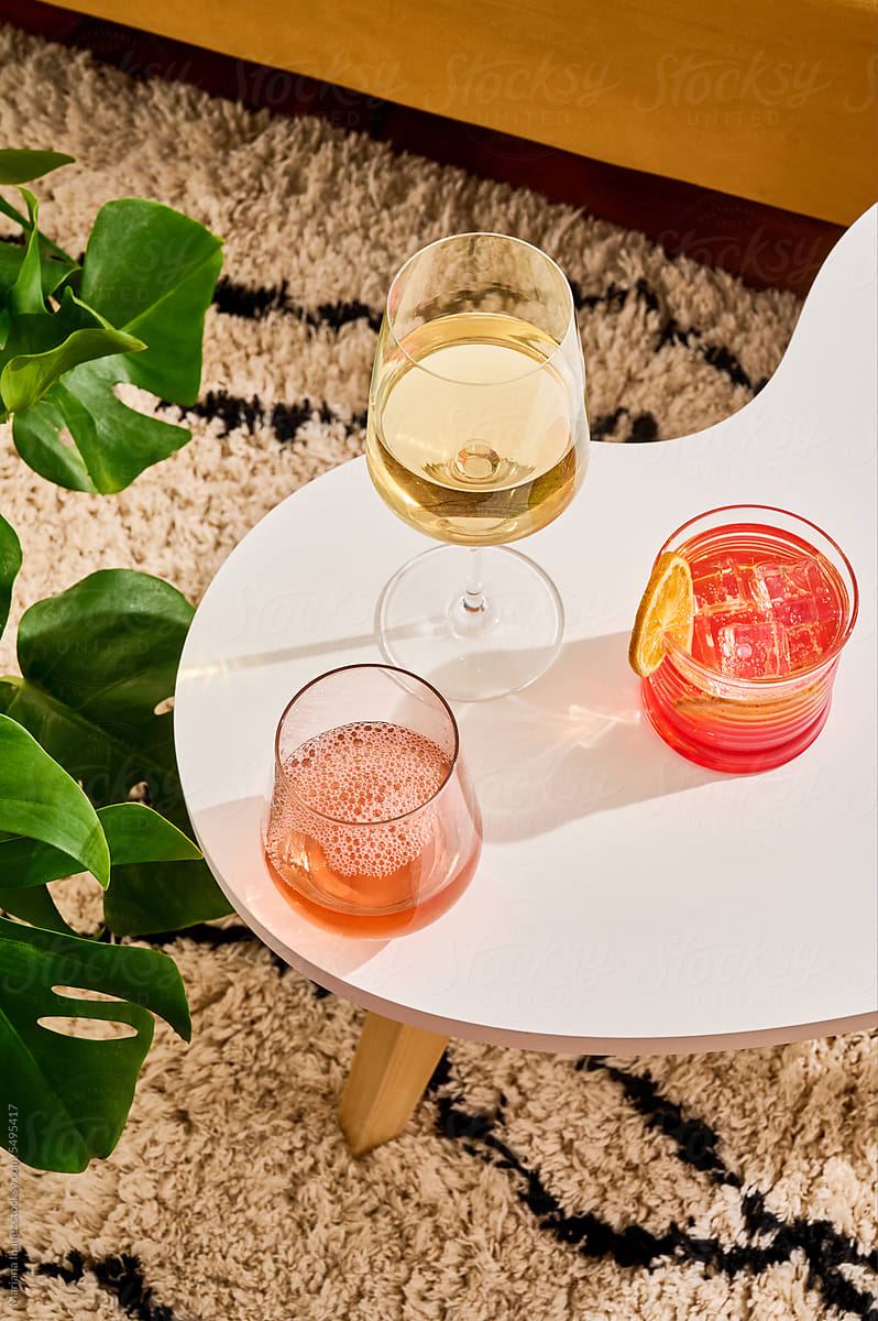 Glass of white wine, rose and cocktail in living room