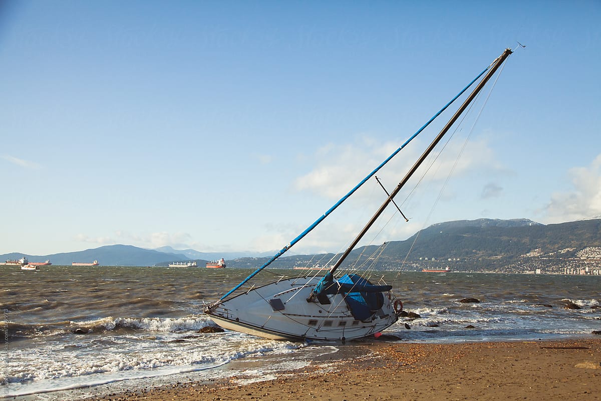 A sail boat washes onto the shore during a big storm.