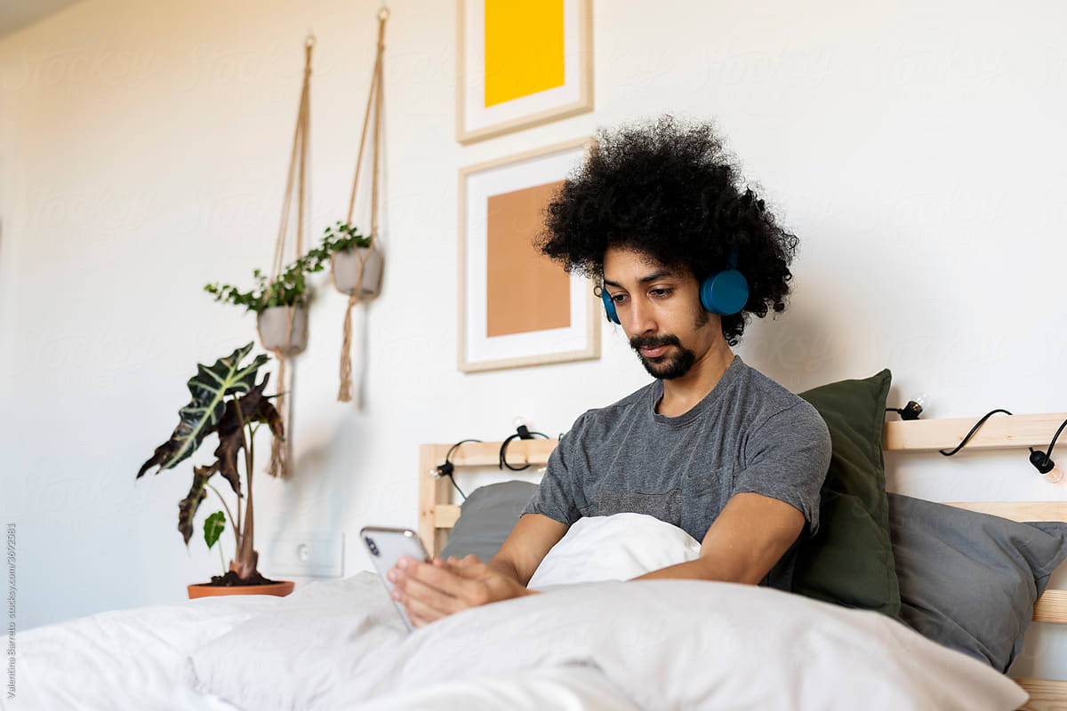 man listen to the music and using smartphone during morning time at bed