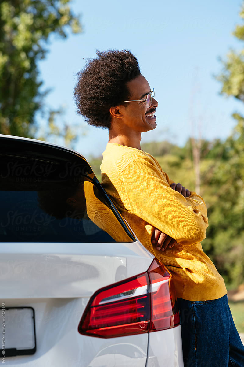 Man leaning on car and laughing