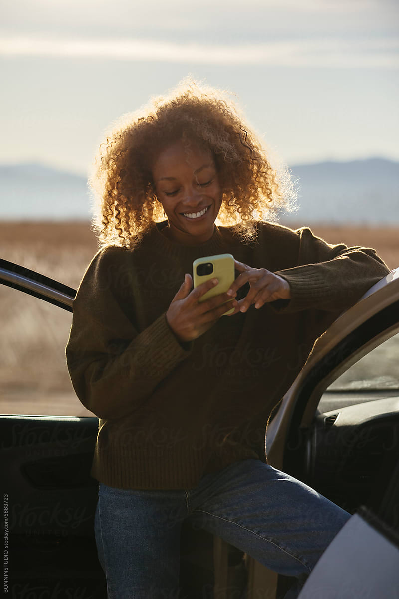 Cheerful woman using smartphone in car
