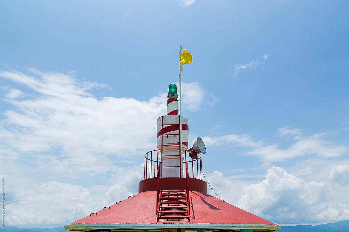 White lighthouse with red lines on a structure with handrail