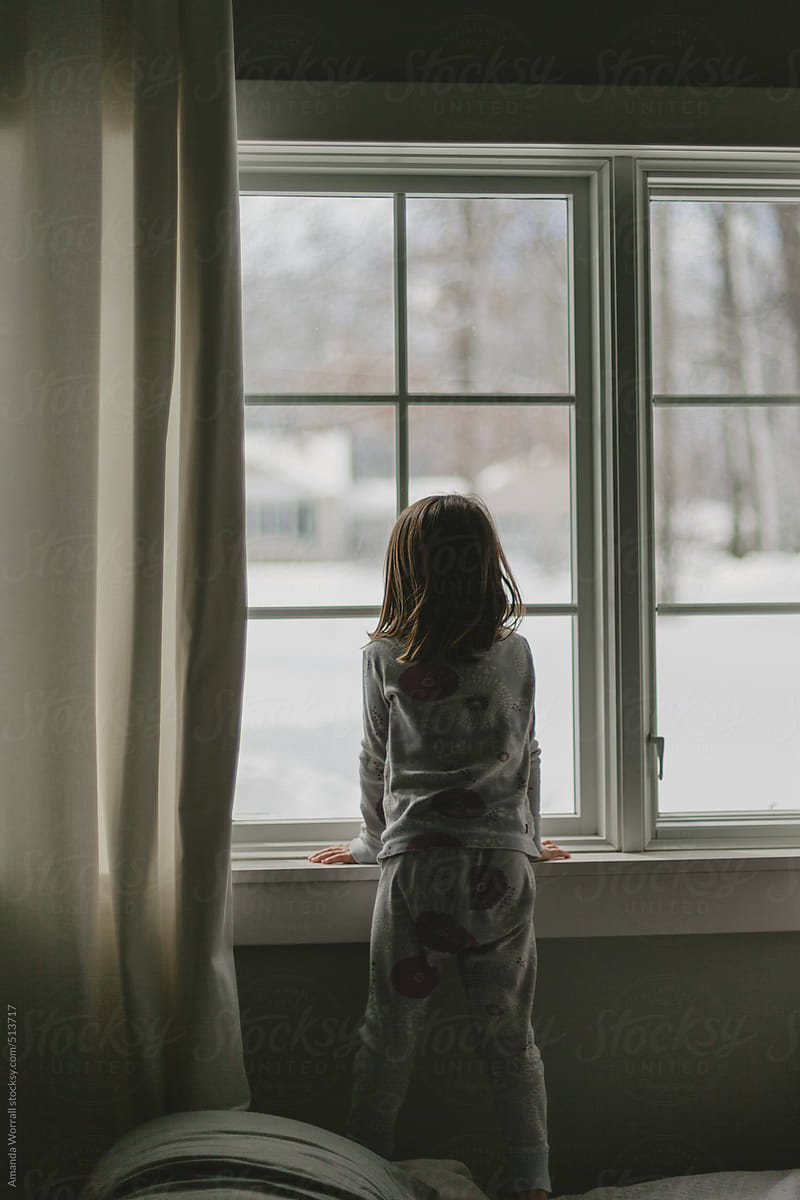 Girl In Pajamas Looking Out Window At Snowy Winter Scene Poramanda Worrall