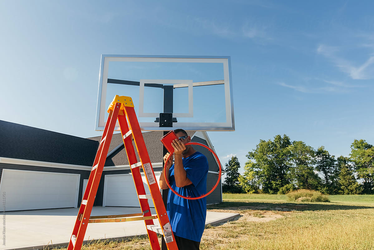 Man screwing parts onto basketball rim.
