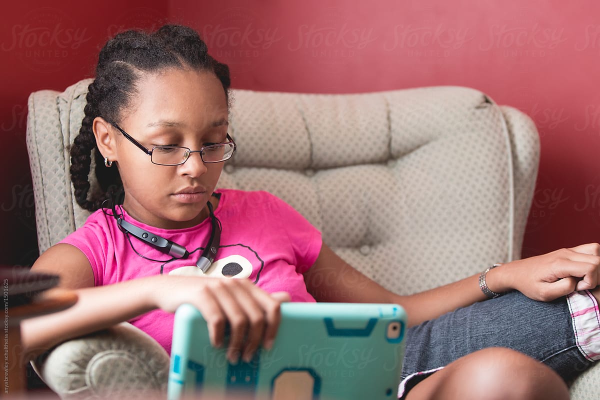 A teenage girl with cornrows using an electronic device